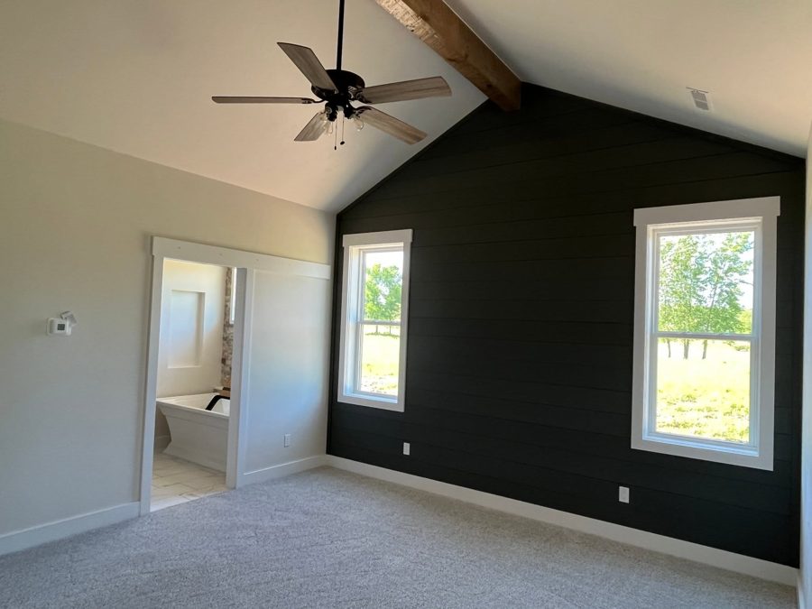 Primary bedroom with a vaulted ceiling and a dark accent wall